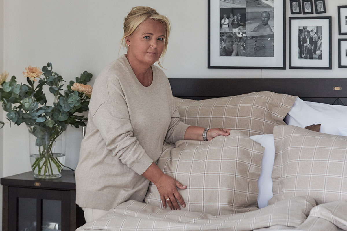 Kristina in 2020 making her bed in last fall's flannel bedding.